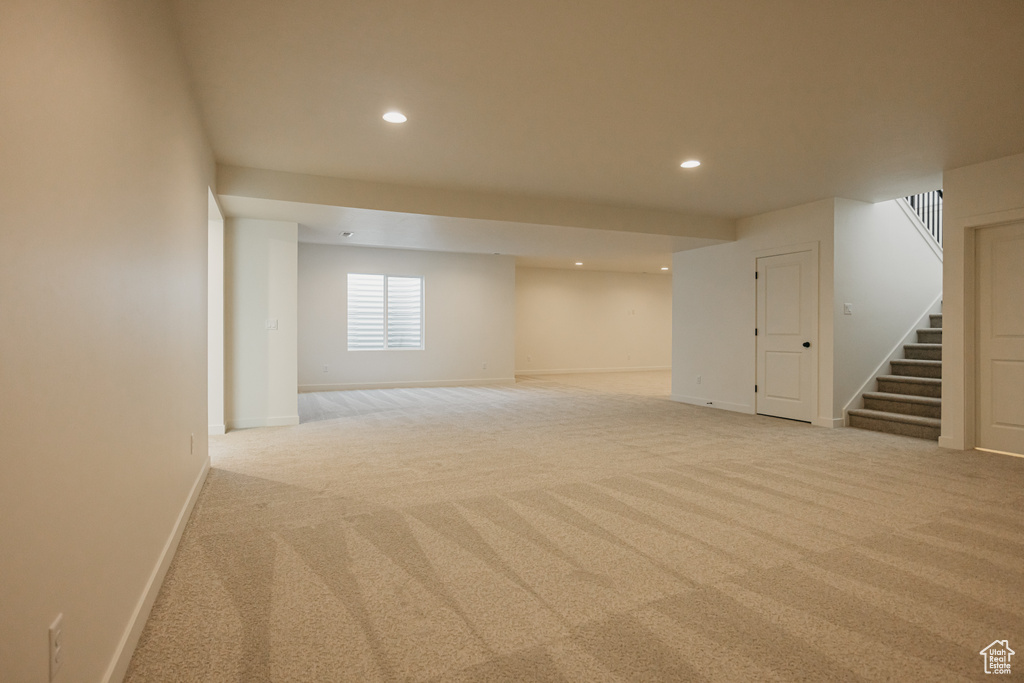 Basement featuring light carpet, recessed lighting, stairs, and baseboards
