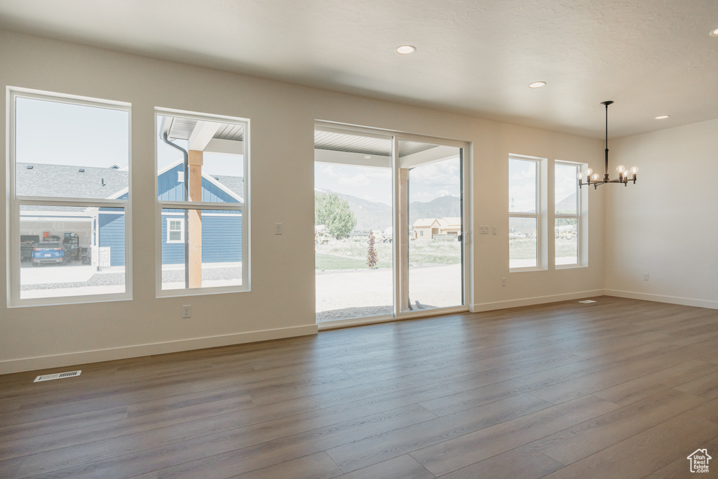 Unfurnished living room with a chandelier, wood finished floors, baseboards, recessed lighting, and a mountain view