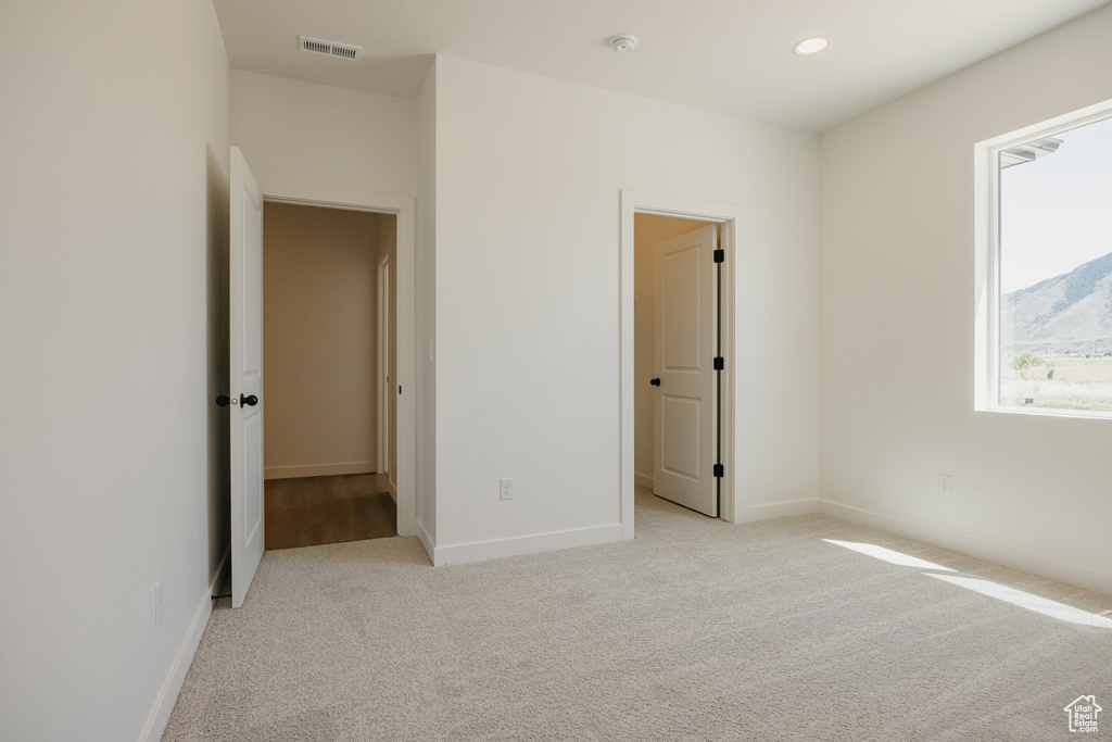 Unfurnished bedroom with light colored carpet, baseboards, and recessed lighting