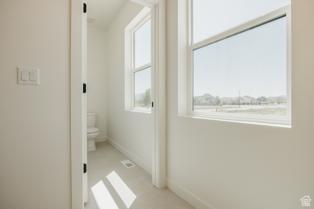 Bathroom with plenty of natural light, toilet, baseboards, and tile patterned flooring