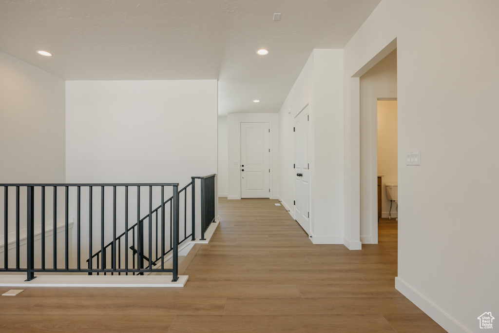 Hallway featuring an upstairs landing, light wood-style floors, baseboards, and recessed lighting