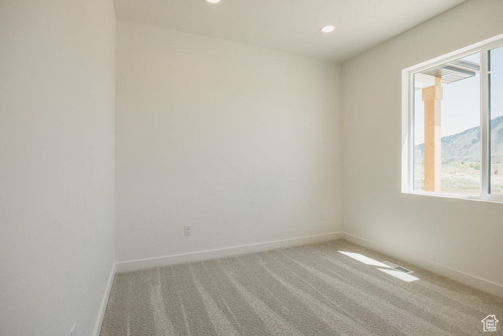 Unfurnished room featuring baseboards, light colored carpet, recessed lighting, and a mountain view