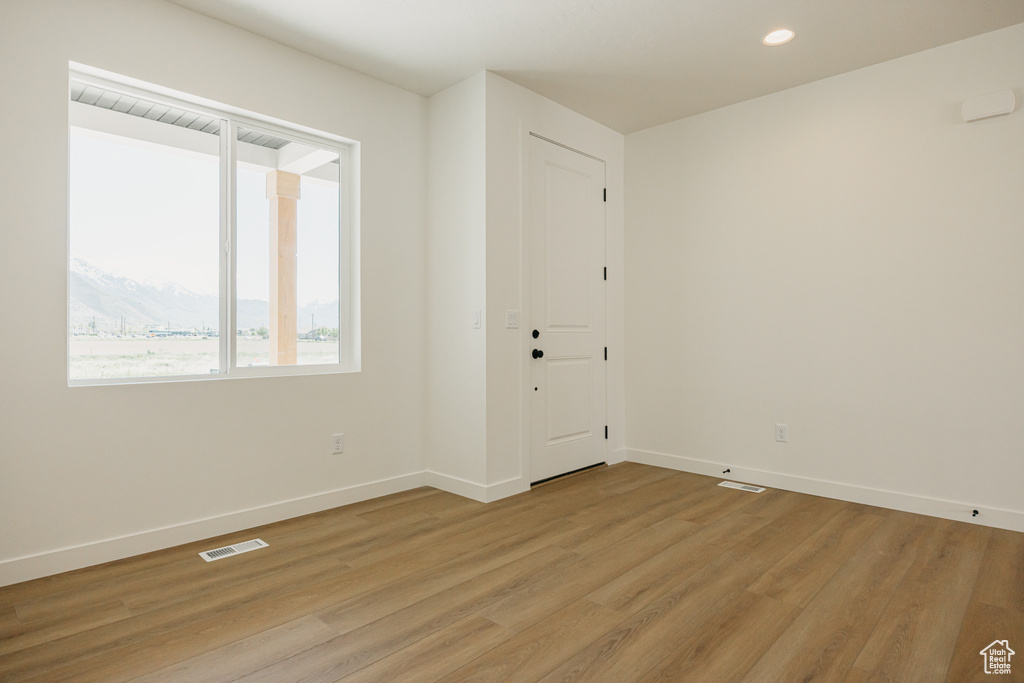 Spare room with light wood-type flooring, baseboards, and recessed lighting