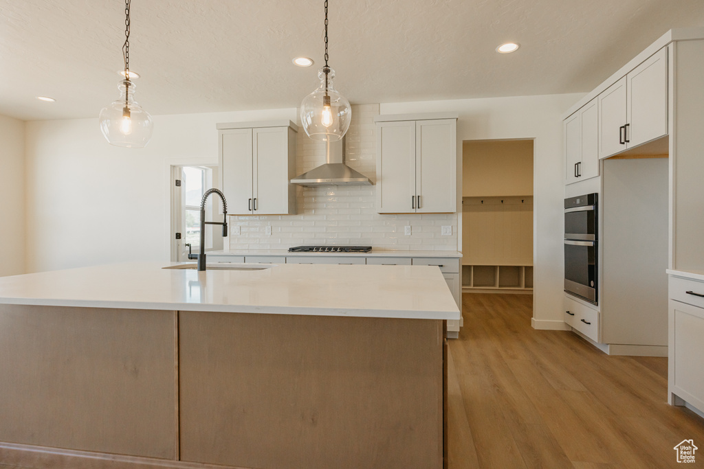 Kitchen featuring a sink, light wood-type flooring, decorative backsplash, recessed lighting, and light countertops