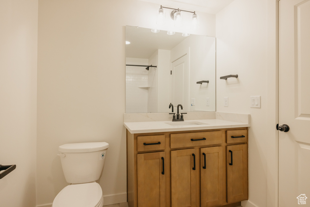 Full bathroom with toilet, vanity, and baseboards