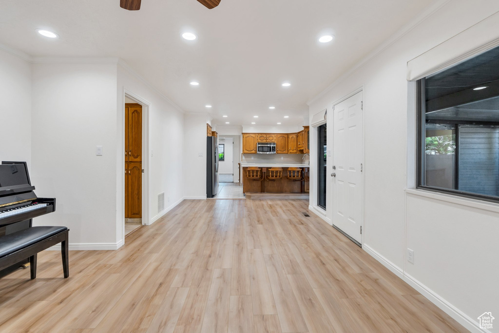 Unfurnished living room featuring light wood-style floors, recessed lighting, a ceiling fan, and ornamental molding