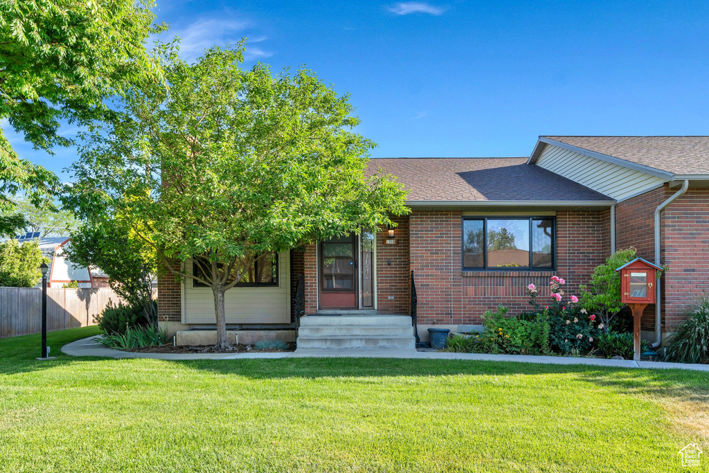 View of front facade featuring brick siding and a shingled roof