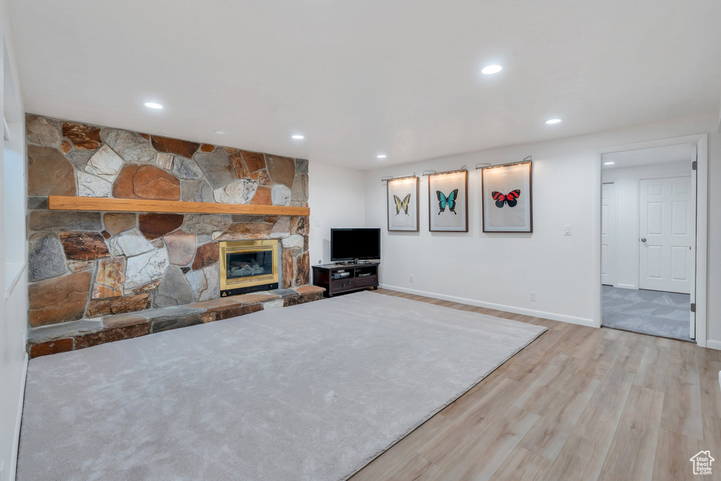 Unfurnished living room with wood finished floors, recessed lighting, and a stone fireplace
