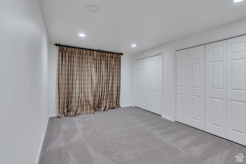 Unfurnished bedroom featuring carpet, recessed lighting, and multiple closets