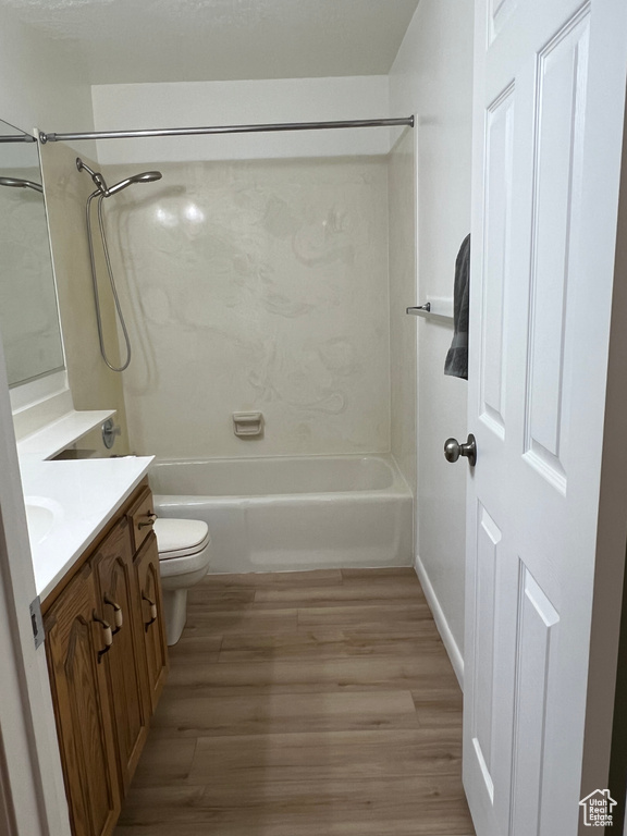 Bathroom featuring tub / shower combination, vanity, toilet, and wood finished floors