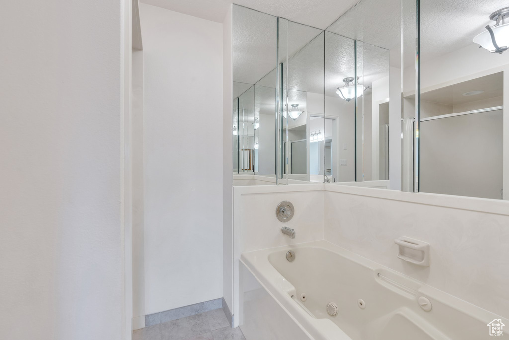 Full bath with a tub with jets, tile patterned floors, and a stall shower