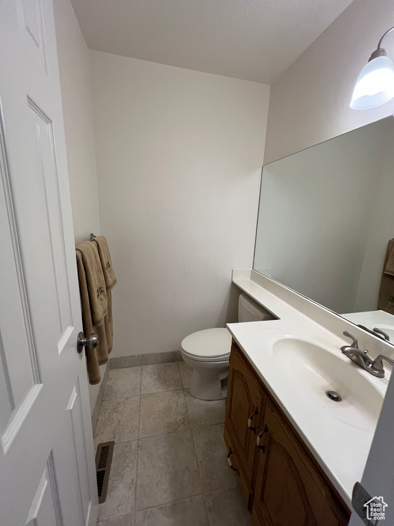 Half bath featuring visible vents, toilet, vanity, and baseboards