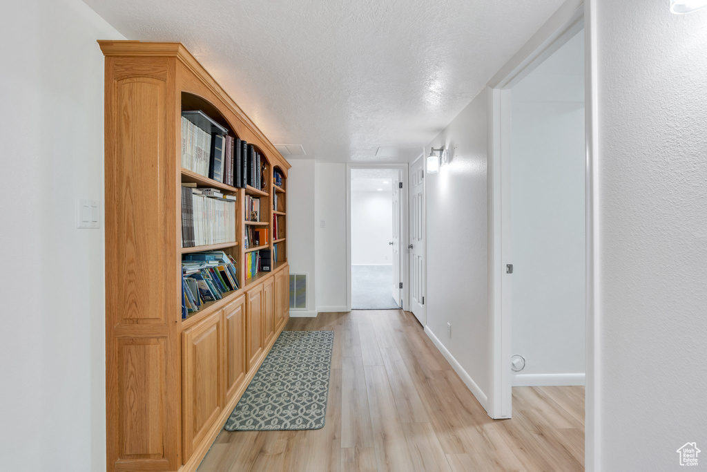 Corridor with light wood-style floors and a textured ceiling