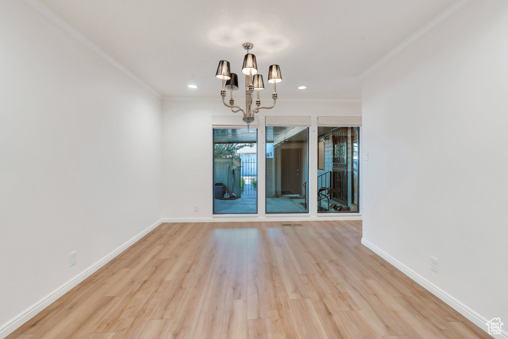 Spare room with a chandelier, wood finished floors, crown molding, and recessed lighting