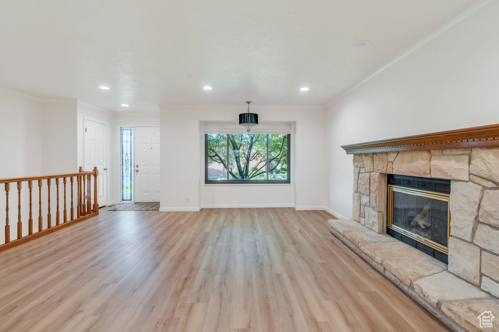 Unfurnished living room with light wood-type flooring, ornamental molding, a fireplace, and recessed lighting