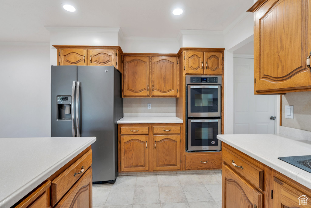 Kitchen featuring appliances with stainless steel finishes, crown molding, light countertops, brown cabinetry, and recessed lighting