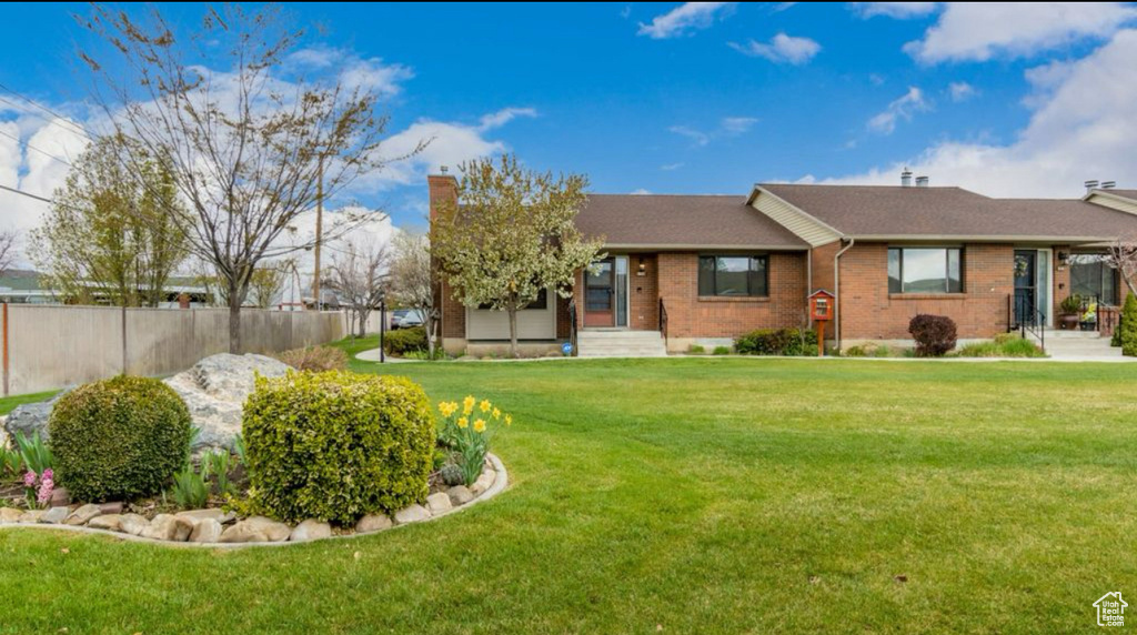 View of front of house featuring a front yard, brick siding, and fence