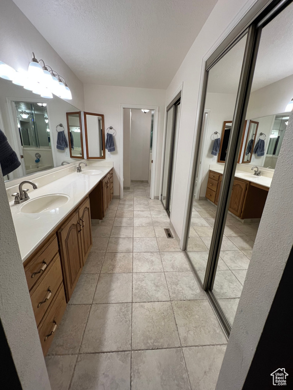 Bathroom with a sink, double vanity, and a textured ceiling