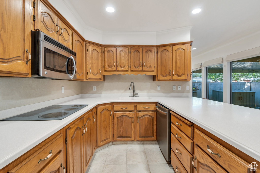 Kitchen featuring stainless steel appliances, brown cabinets, light countertops, recessed lighting, and light tile patterned floors