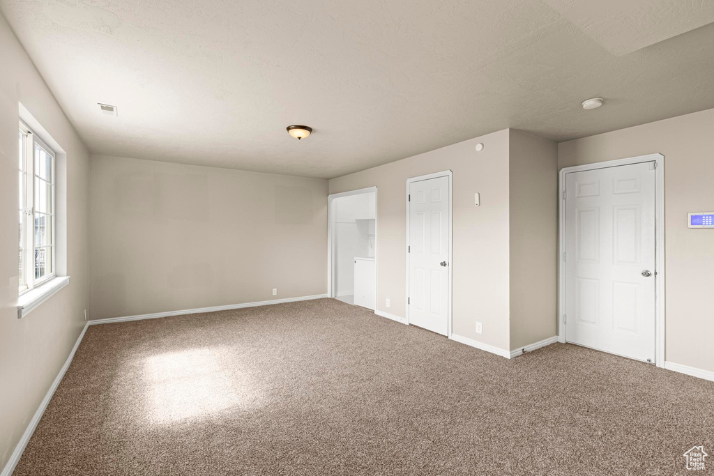 Unfurnished bedroom with visible vents, baseboards, and carpet