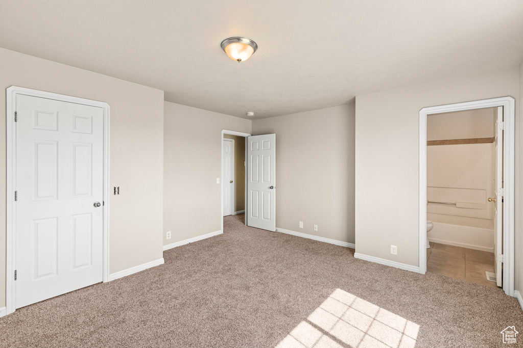 Unfurnished bedroom with carpet floors, baseboards, and ensuite bath