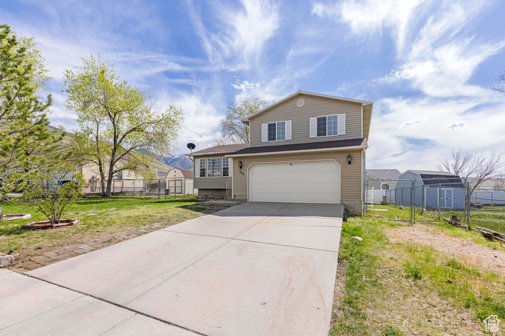 View of front of home featuring concrete driveway, fence, and an attached garage