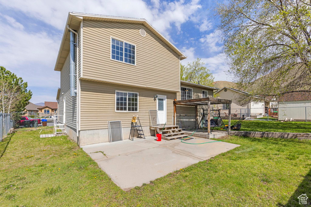 Back of property with a yard, a fenced backyard, entry steps, and a patio