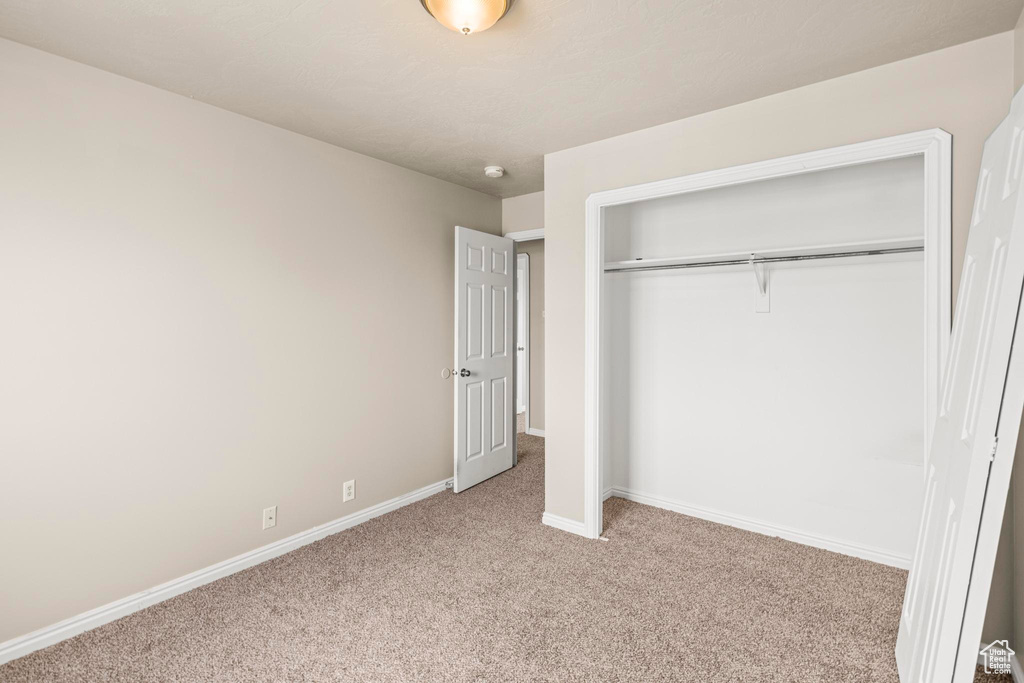 Unfurnished bedroom with carpet floors, baseboards, and a closet
