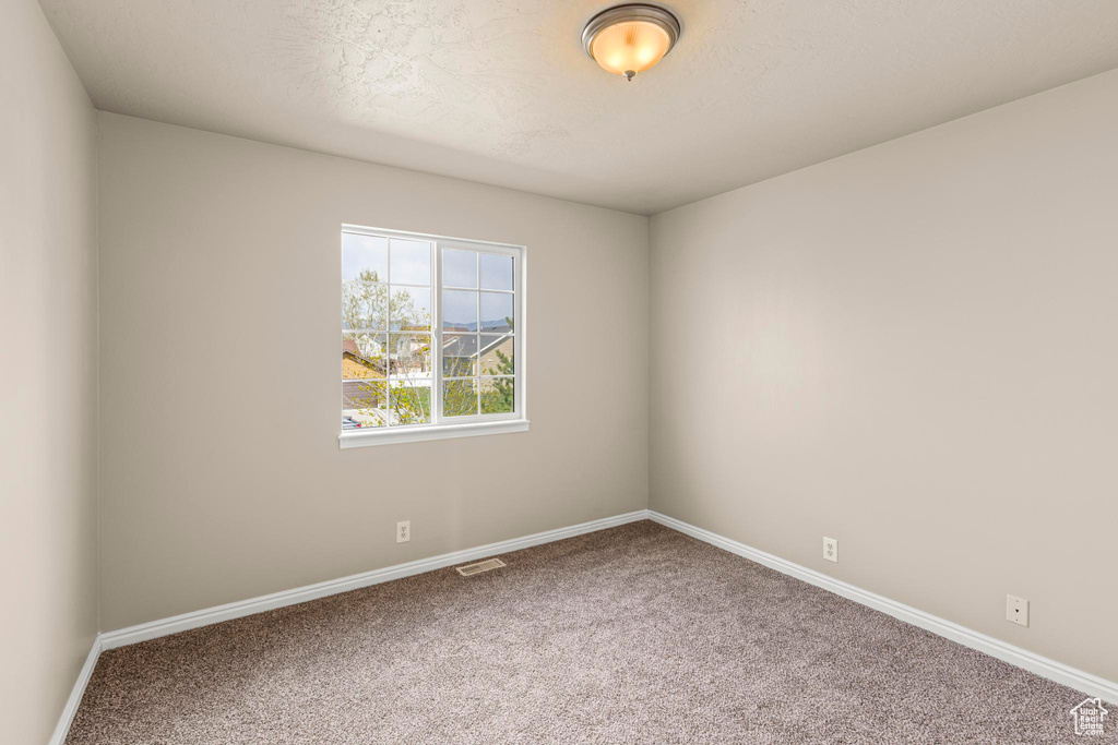 Carpeted spare room featuring baseboards and visible vents