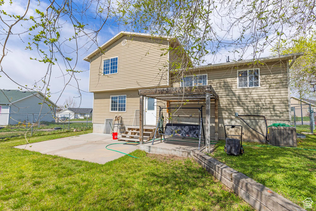Back of property featuring a pergola, a patio, fence, and a lawn
