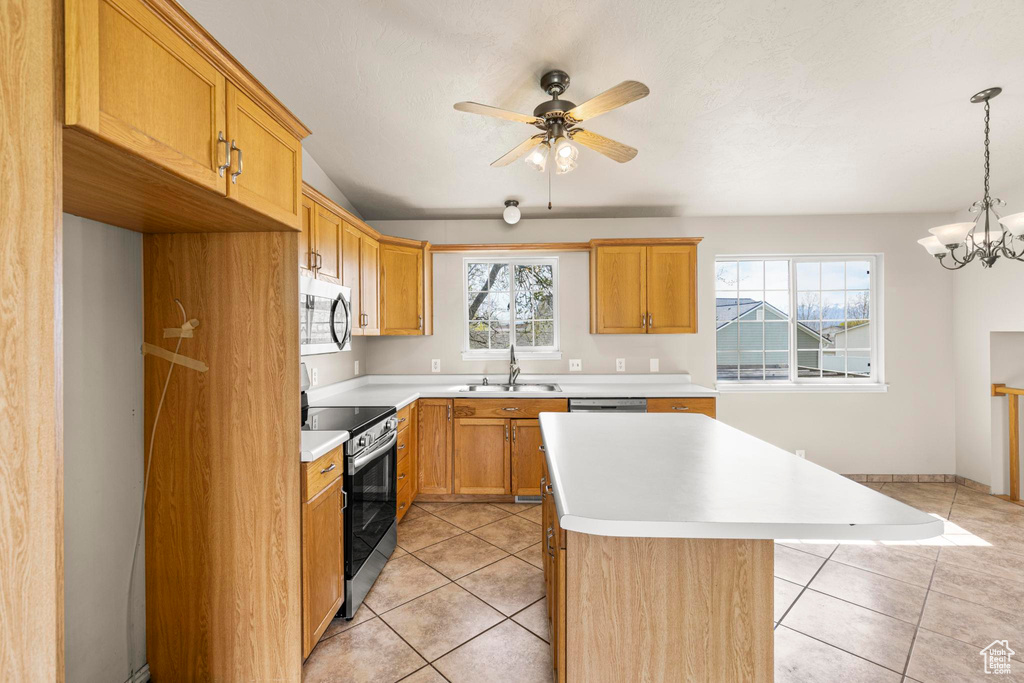 Kitchen with light tile patterned floors, a kitchen island, appliances with stainless steel finishes, light countertops, and a sink