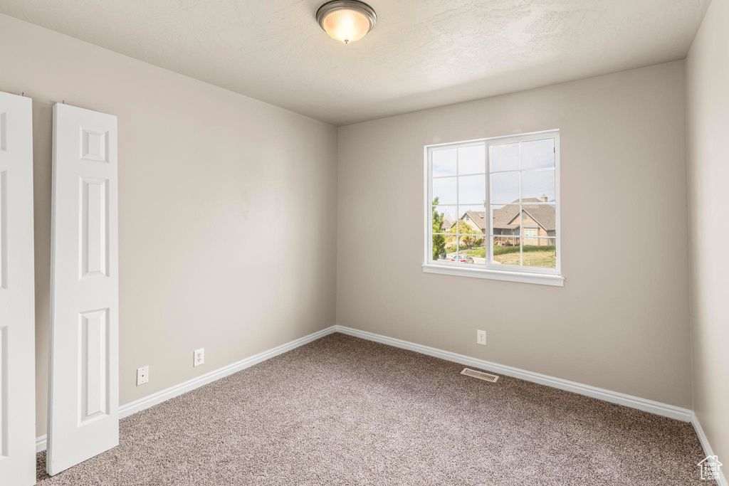 Carpeted empty room with visible vents and baseboards