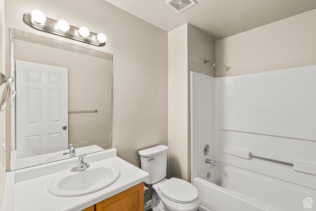 Bathroom with bathing tub / shower combination, vanity, visible vents, and toilet