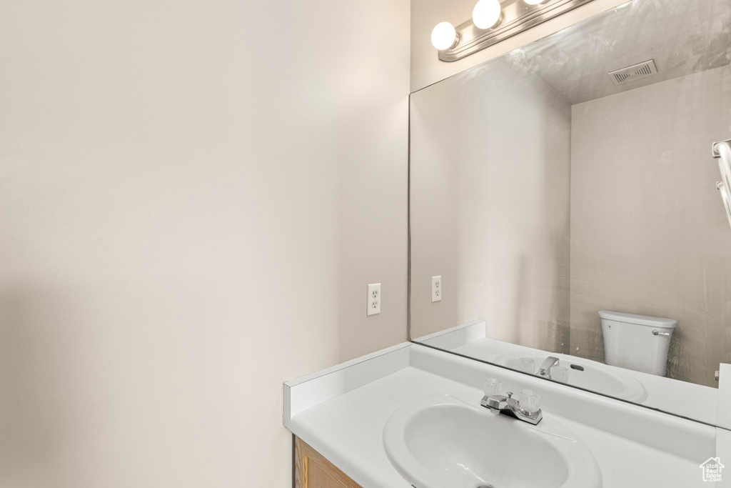Bathroom with toilet, vanity, and visible vents