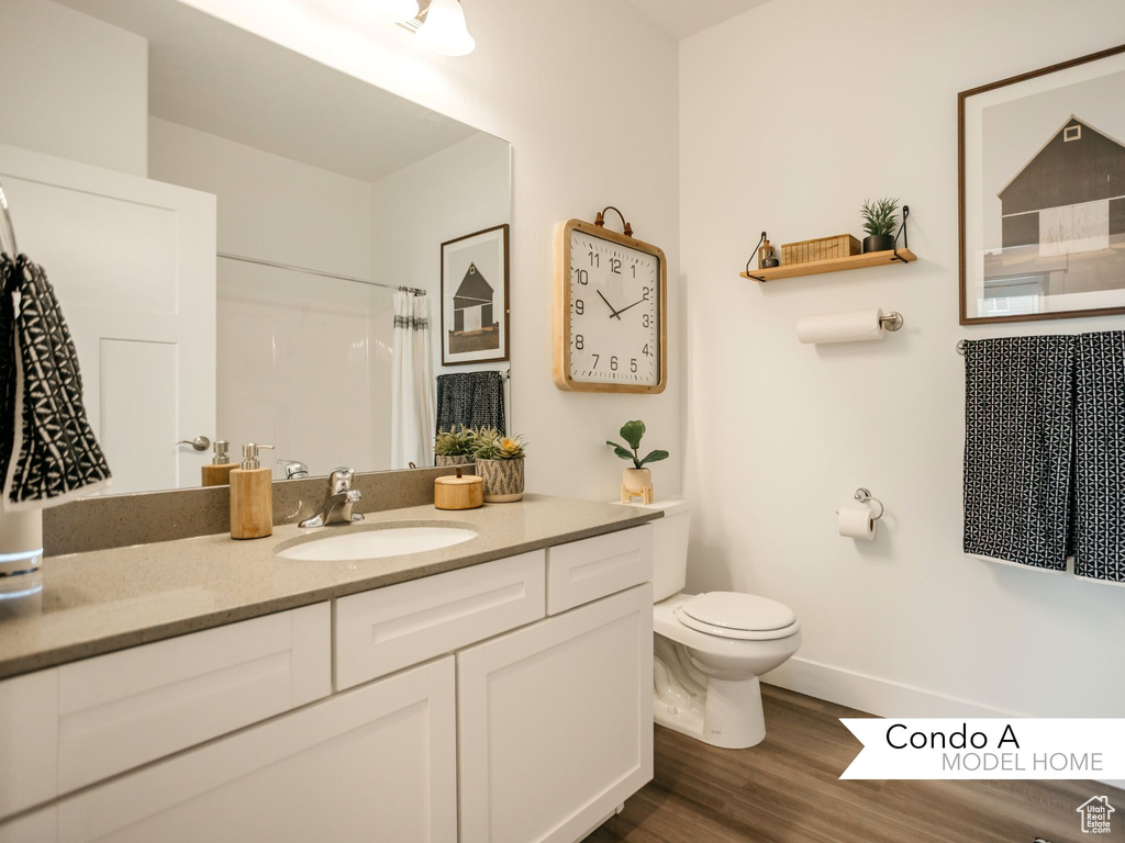 Full bath with baseboards, a shower with shower curtain, toilet, vanity, and wood finished floors