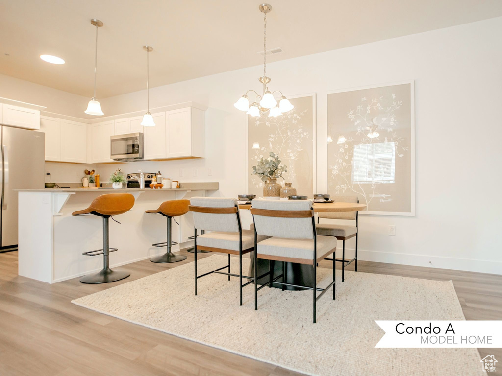 Dining space with a chandelier, light wood finished floors, visible vents, and baseboards