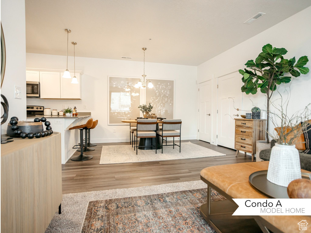 Living area with a chandelier, visible vents, baseboards, and wood finished floors