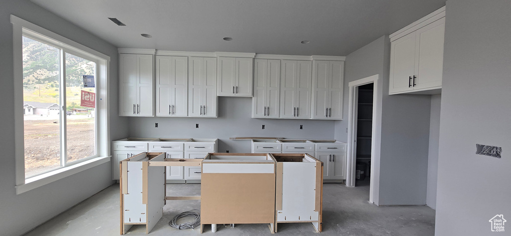 Kitchen featuring white cabinetry, concrete flooring, and a center island
