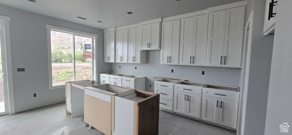 Kitchen featuring white cabinets, a center island, and concrete floors