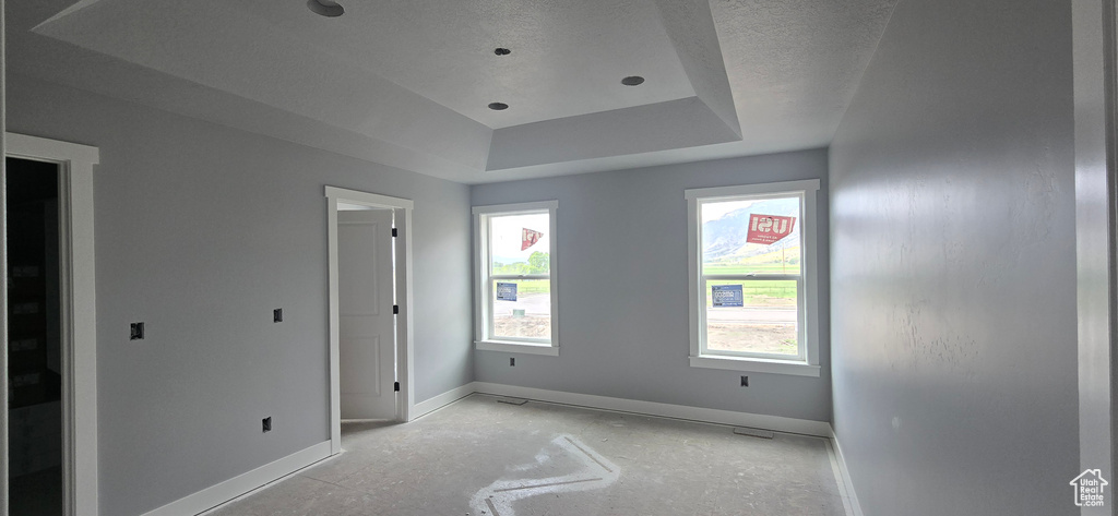Unfurnished bedroom featuring baseboards, a raised ceiling, and a textured ceiling