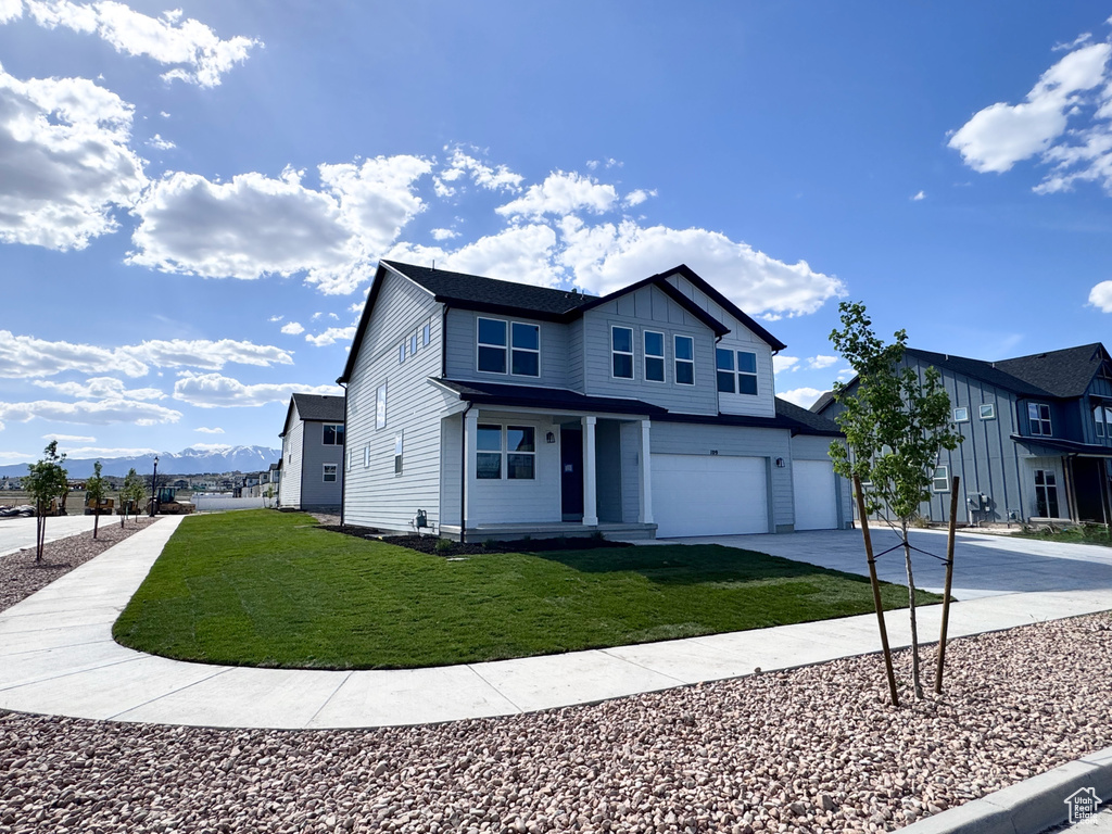 View of front of property with a garage, driveway, a front yard, board and batten siding, and a porch