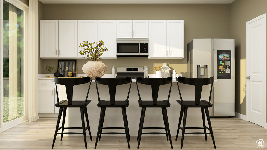 Kitchen featuring white cabinets, stainless steel fridge with ice dispenser, light wood finished floors, and stove