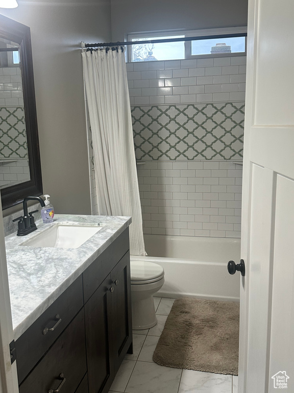 Full bathroom with marble finish floor, toilet, vanity, and shower / bath combo with shower curtain