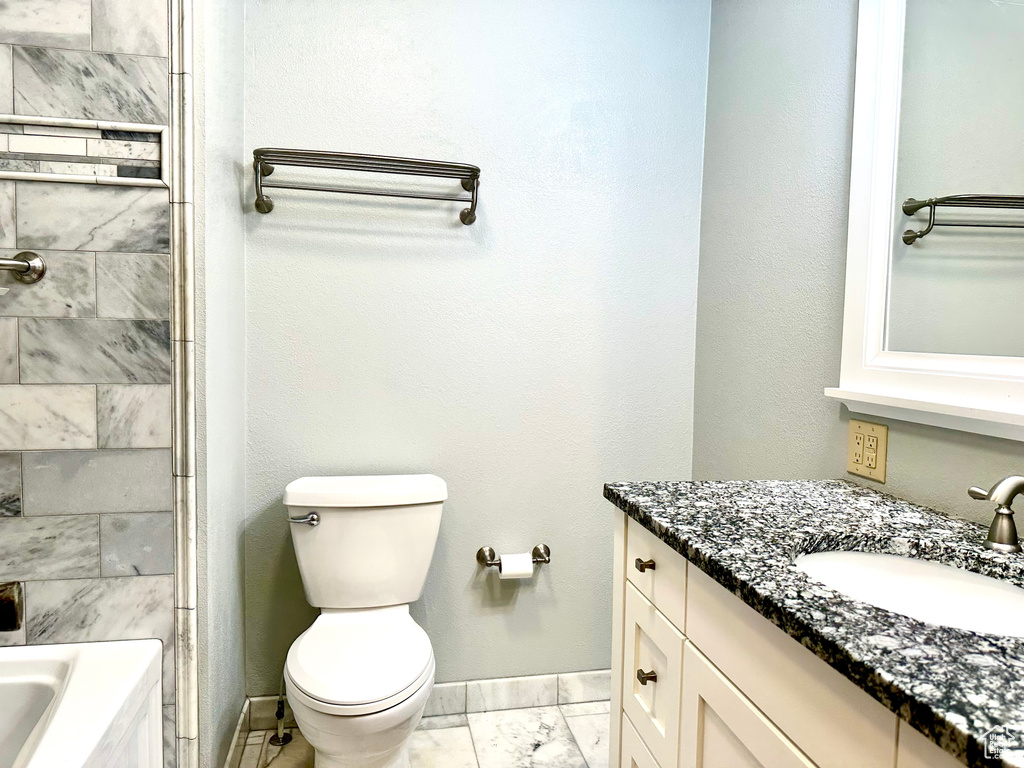 Full bath featuring vanity, baseboards, marble finish flooring, and toilet