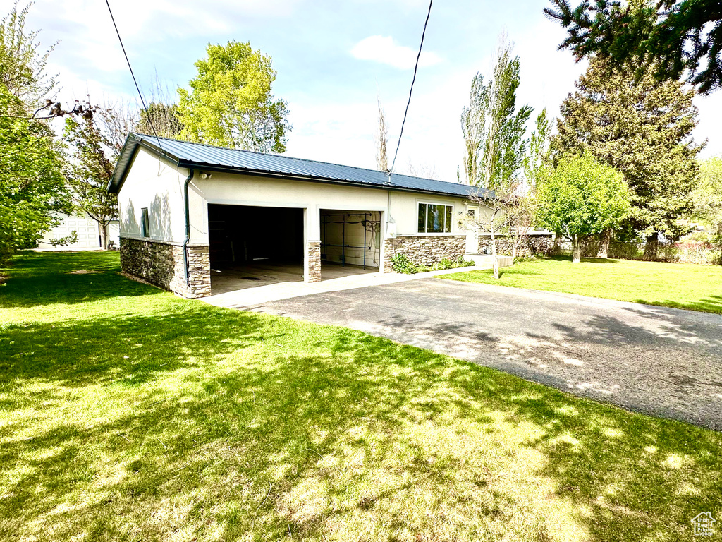 View of home\\\'s exterior with stone siding, stucco siding, asphalt driveway, and a lawn