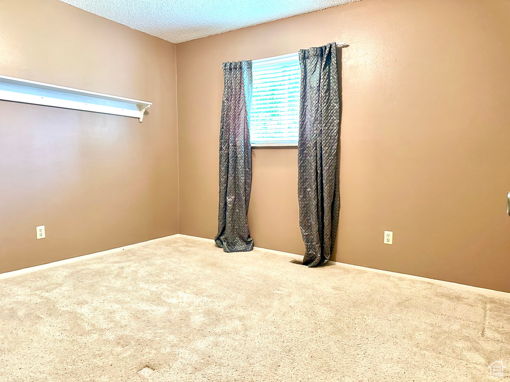 Unfurnished room with carpet, baseboards, and a textured ceiling