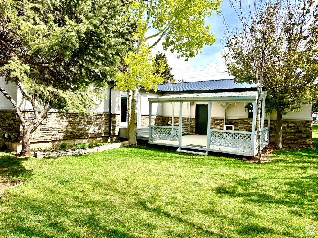 Back of property with stone siding and a yard