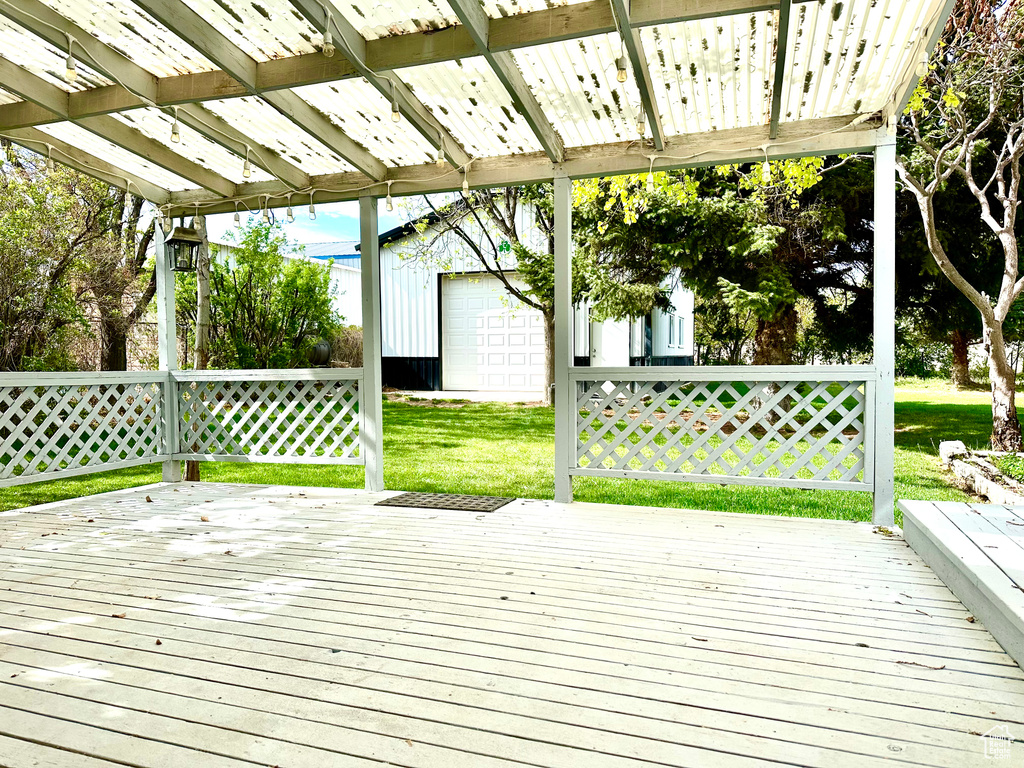 Wooden deck with a lawn, an outdoor structure, and a garage