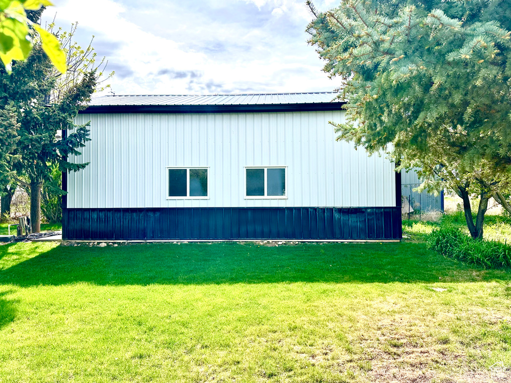 View of side of home with a lawn and metal roof