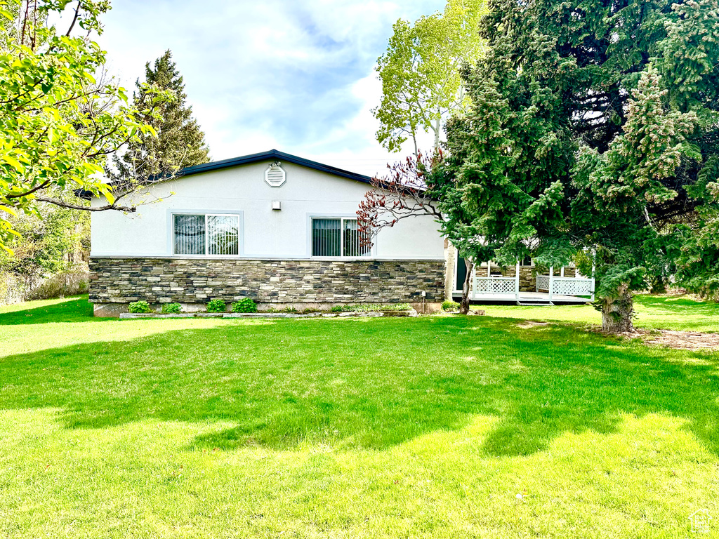 View of home\\\'s exterior with stucco siding, a lawn, and stone siding